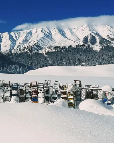 Snow-covered ski equipment with majestic Himalayan peaks in Gulmarg